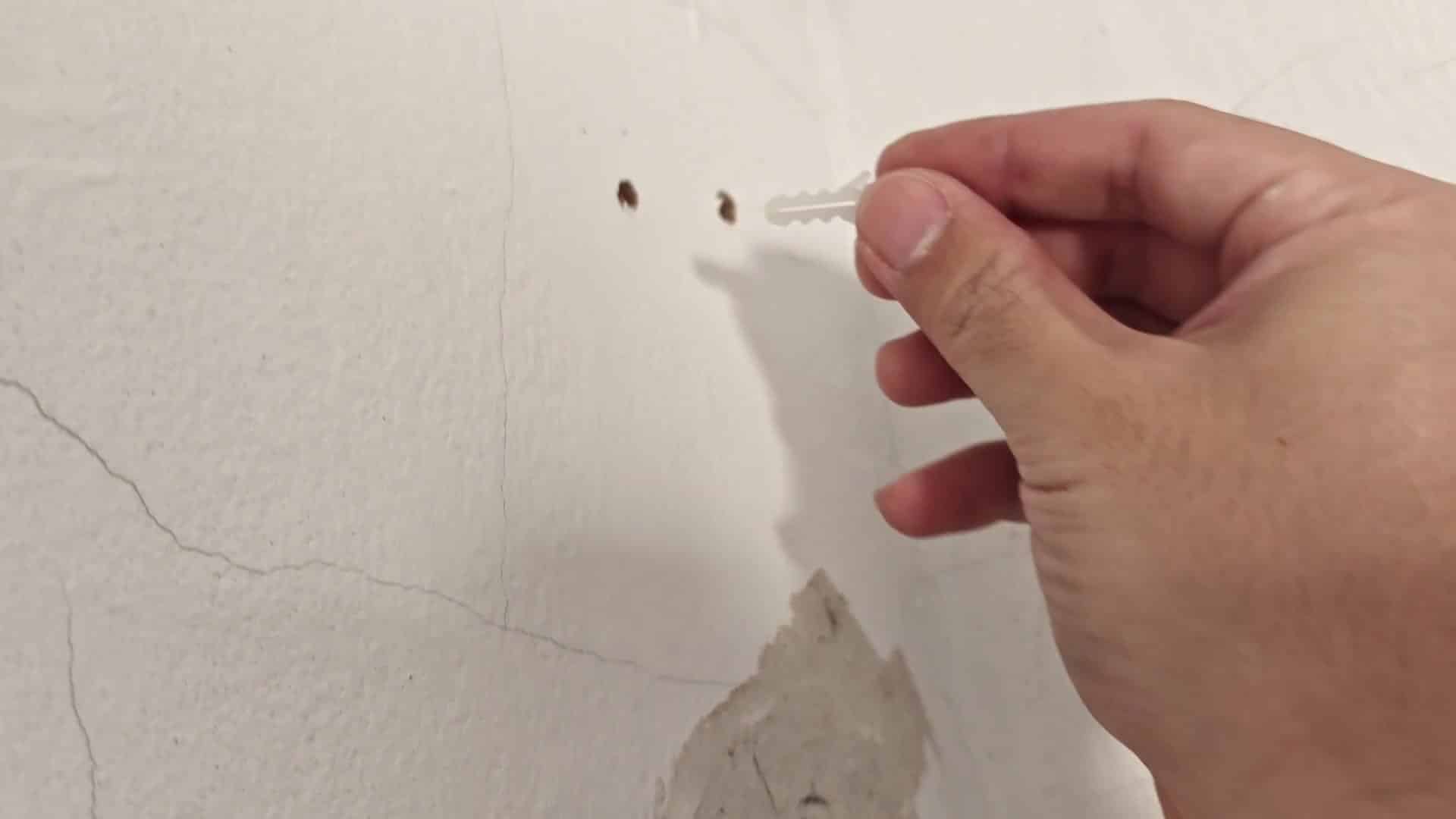 Inserting white wall anchor into hole Inserting white wall anchor into hole
