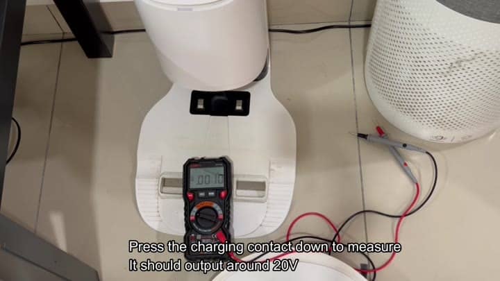 Multimeter resting on robot vacuum base Multimeter resting on robot vacuum base