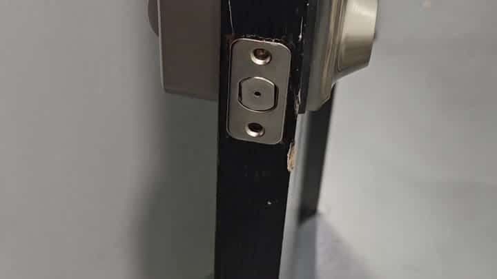 Metal strike plate mounted on black door edge Metal strike plate mounted on black door edge